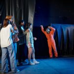 interracial people engaged in escape room challenge hiding from man in gas mask and orange ppe suit