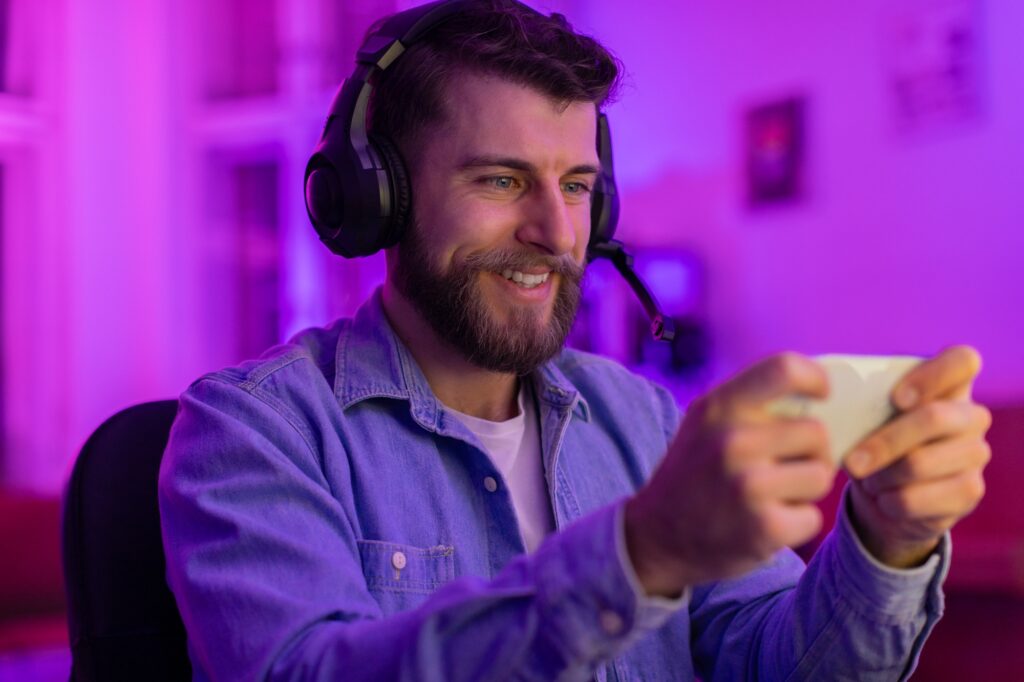 Man playing games on smartphone with headset